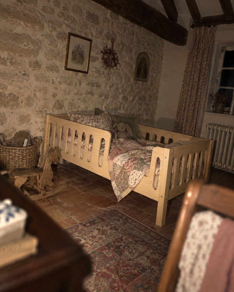 Lit enfant en bois dans une chambre de maison ancienne aux murs de pierre